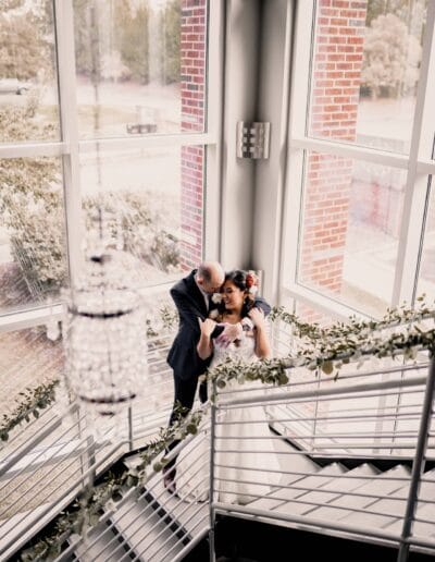 Couple embracing on staircase, elegant setting.